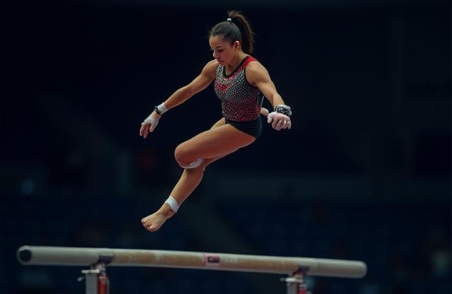 Competitive gymnast performing a routine on the uneven bars